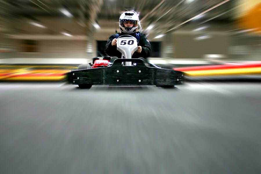 Zwei Männer mit Karts auf einer Kartbahn.