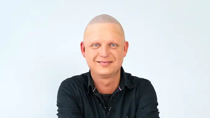 Der Patient Peter N. zufrieden sitzt auf einem Stuhl nach seiner Haarpigmentierung bei Dr. Pigment